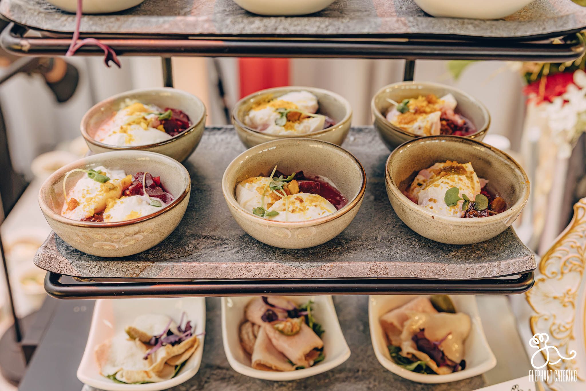 Bowls of dessert with yogurt, fruit, and toppings arranged on a food display rack.
